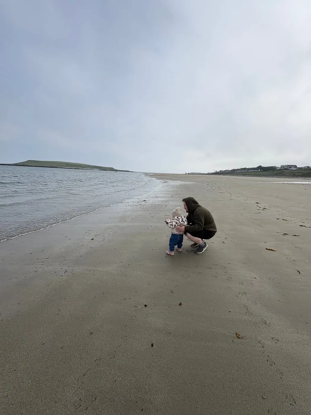 Toddler exploring the shoreline on a breezy beach walk