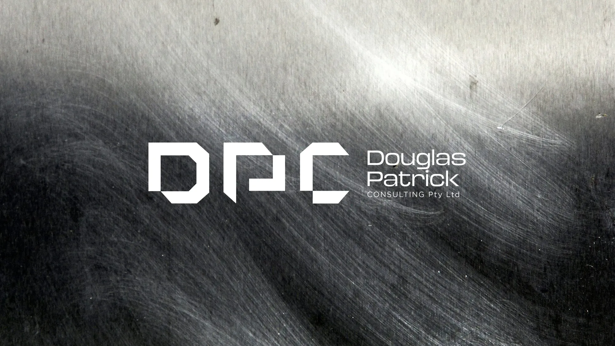 The DPC monogram reversed out of a dark brushed-metal surface